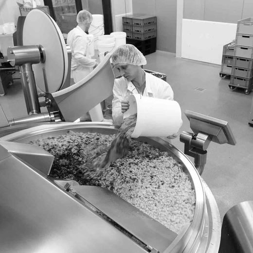 Mitarbeiterin von bio-verde befüllt modernes Mischgerät mit frisch geernteten Produkten